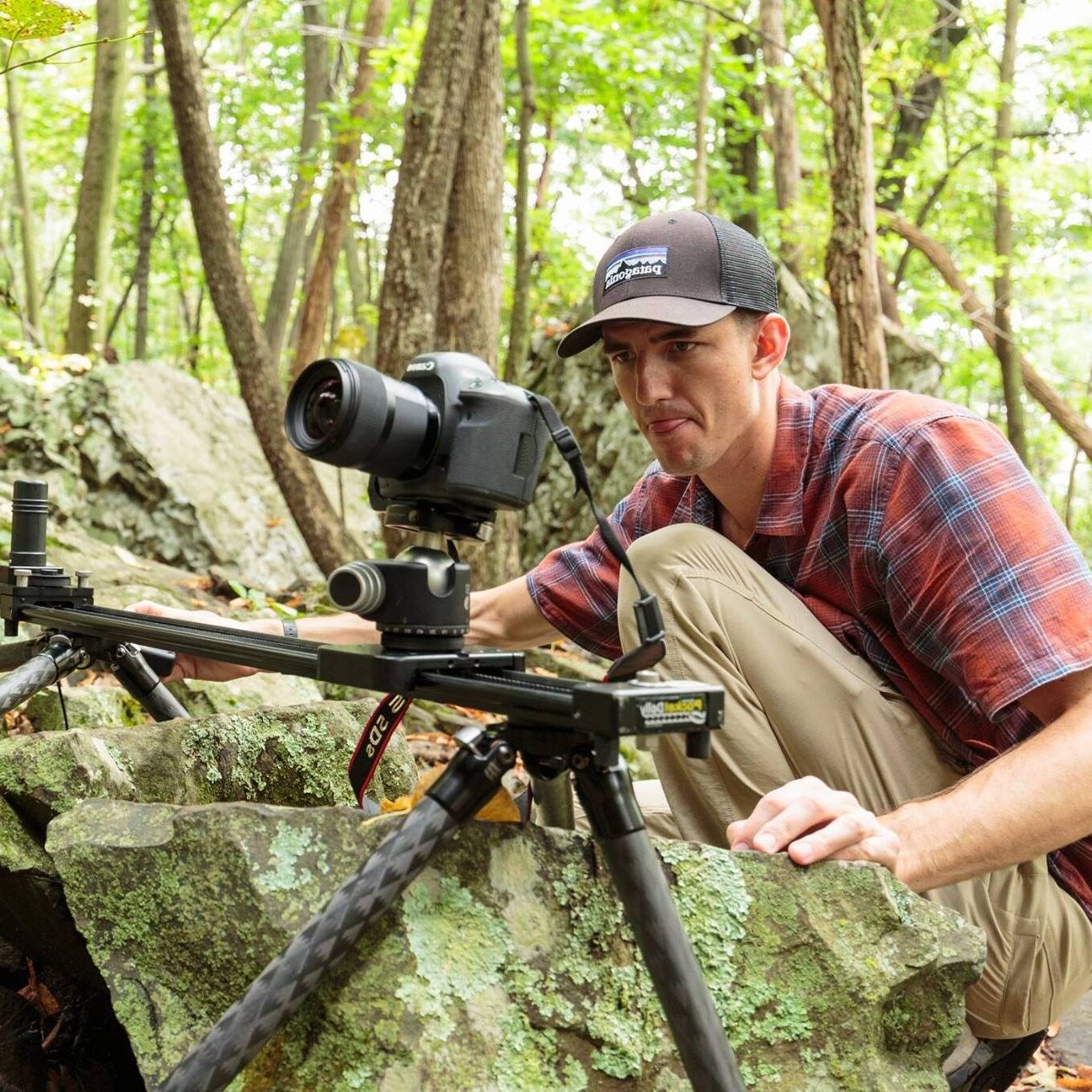 A man looks into a camera set up on a slider above rocks with concentration