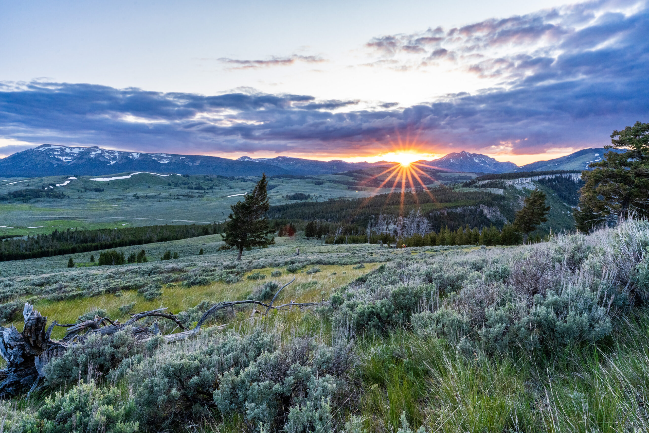 The sun sets behind a distant mountain.